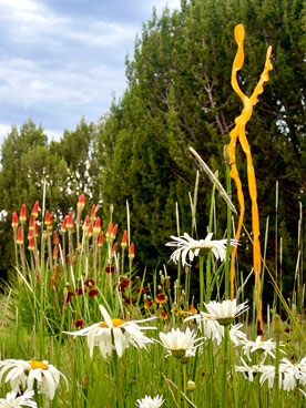 Wildflowers and a tall yellow metal sculpture.